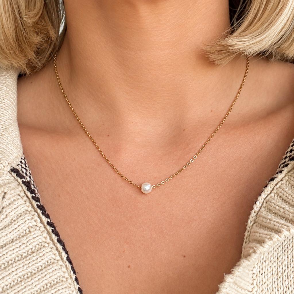 woman wearing dainty gold chain and small pearl necklace-short blonde hair touching shoulders and open cardigan sweater