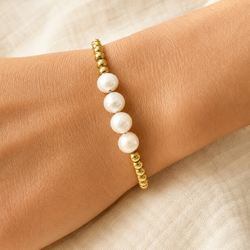 gold bead and four pearl bracelet on model wrist with white background 
