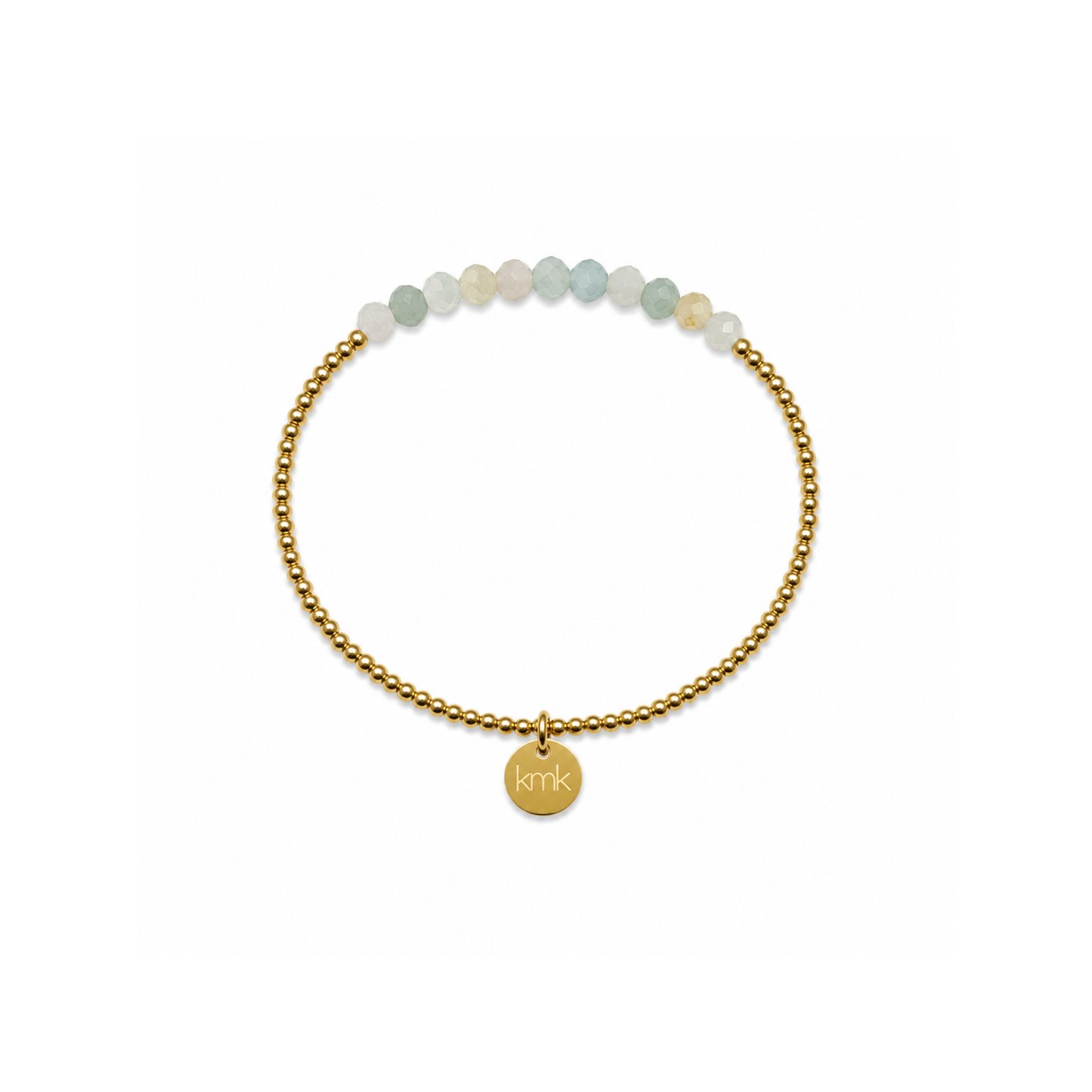 A delicate gold beaded bracelet with a small round gold charm engraved with 'KMK', accented by a row of pale green and white beads at the top, shown on a plain white background.