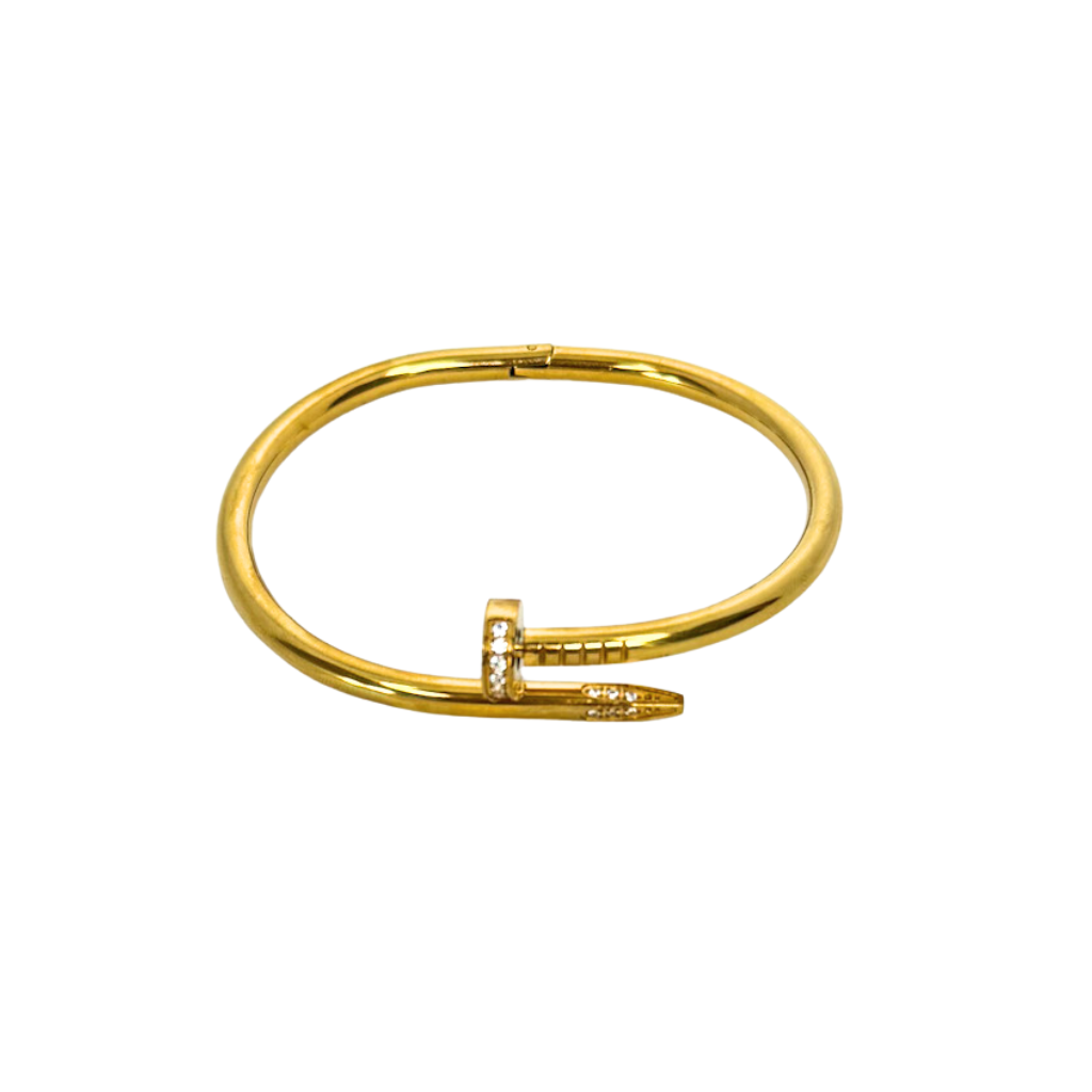 Gold nail bangle bracelet with a small diamond on a white background