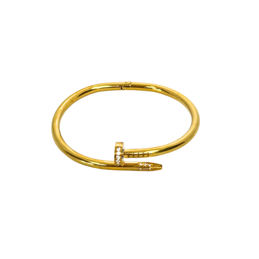 Gold nail bangle bracelet with a small diamond on a white background