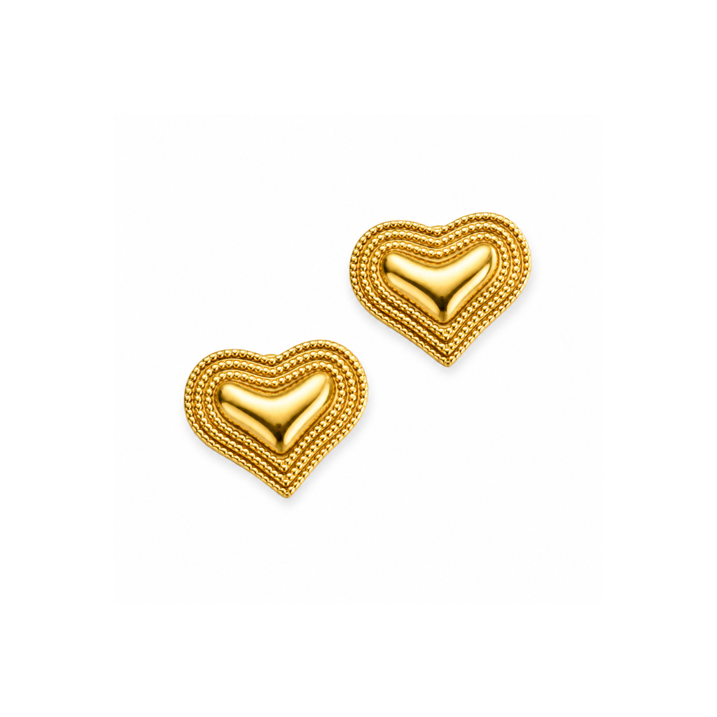 A pair of gold heart-shaped stud earrings with a layered, beaded textured border and a smooth, polished gold center, shown on a plain white background.