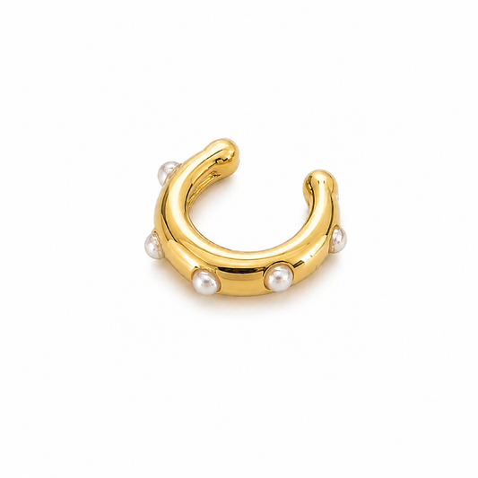A gold crescent-shaped ear cuff with small white pearl accents, photographed on a clean white background.