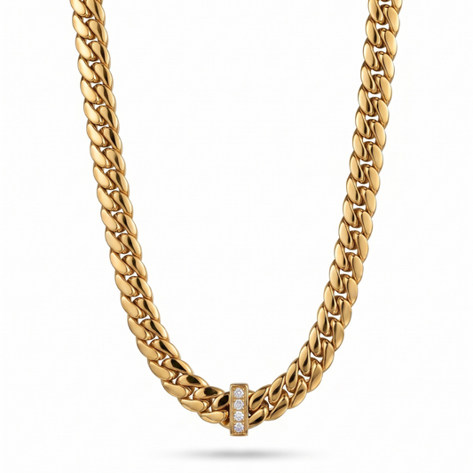 A gold Cuban link chain necklace with a small rectangular gold clasp set with clear stones, shown against a plain white background.